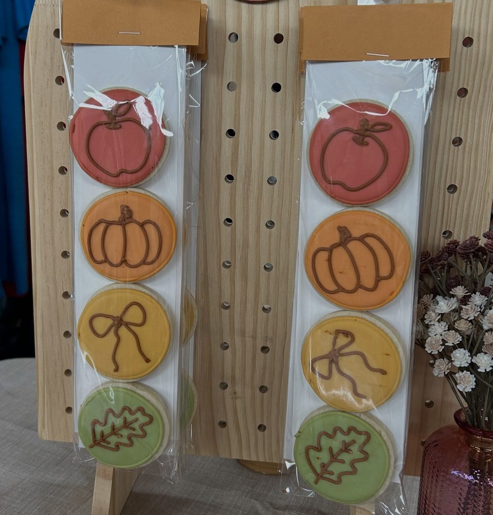 Bagged apple, pumpkin, bow and leaf cookies hanging on a market display